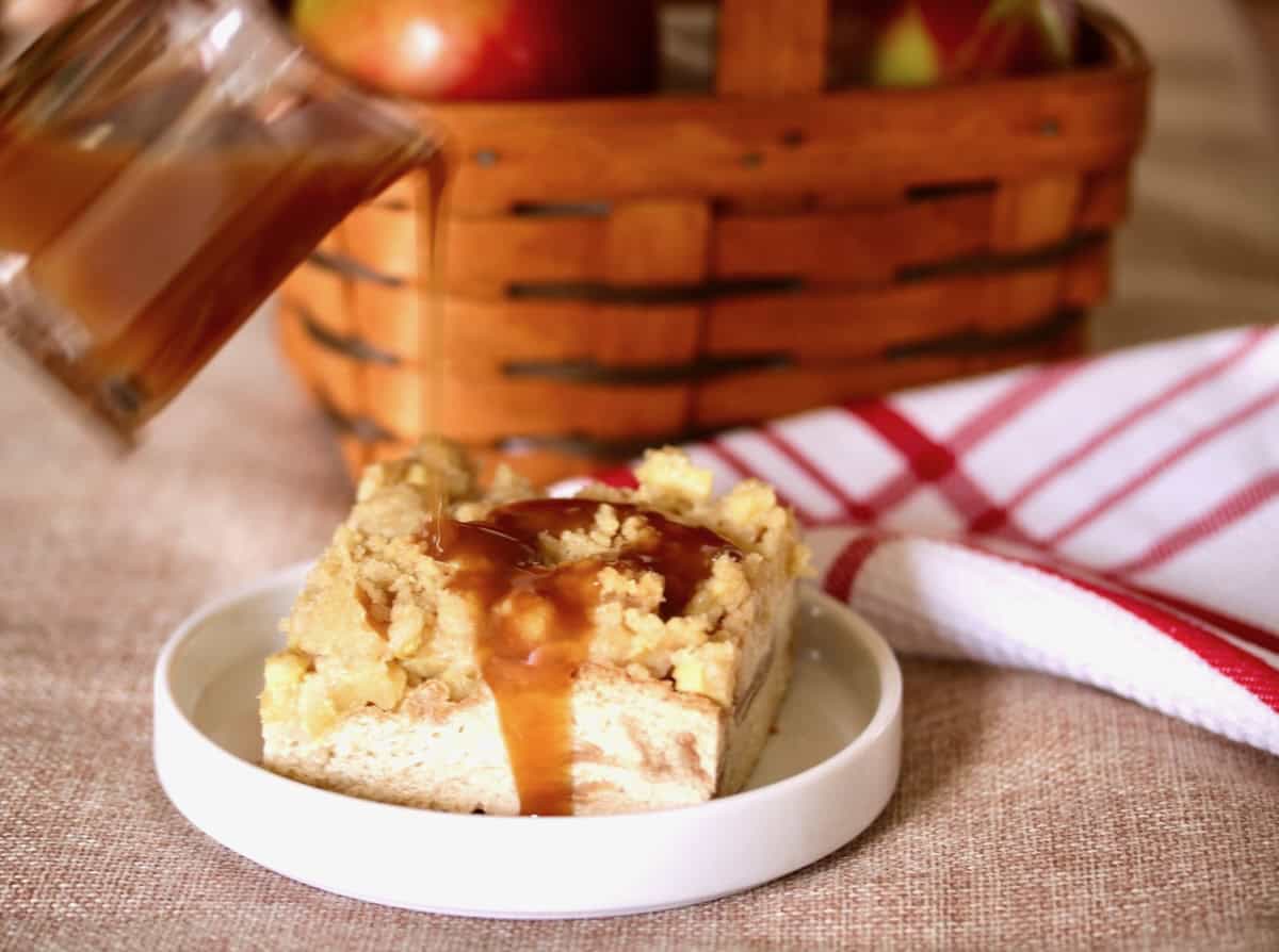 Pouring bourbon caramel sauce on top of apple bread pudding.