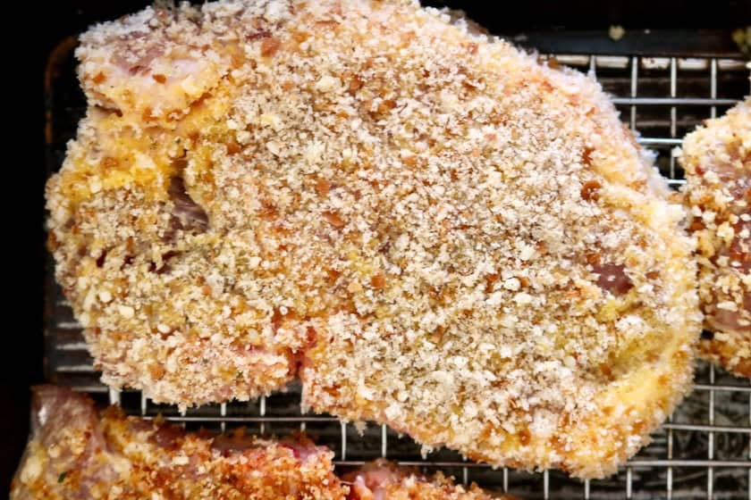 Breaded pork chops on a rack.