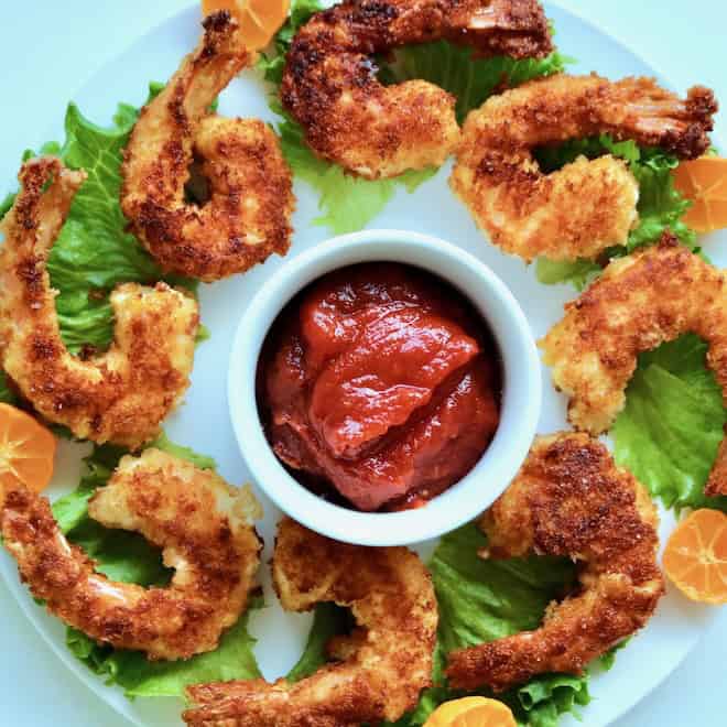 Plated fried shrimp with cocktail sauce.