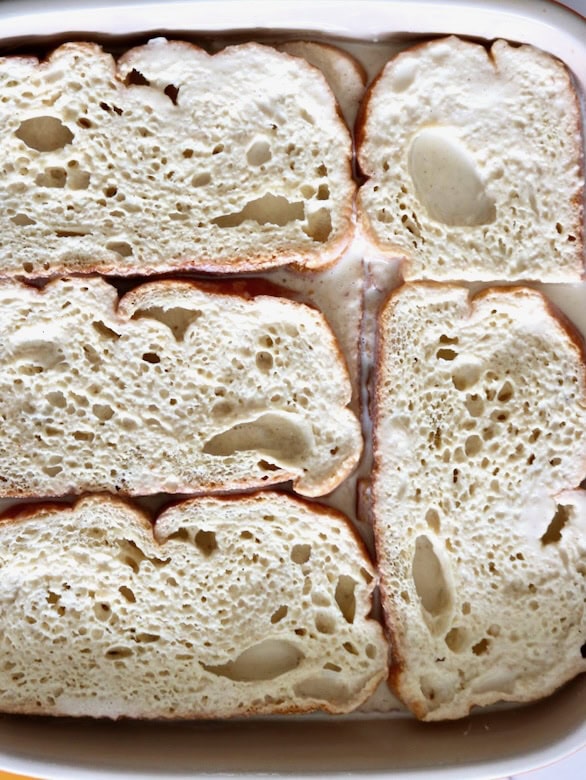 Layers of bread and custard in baking dish.