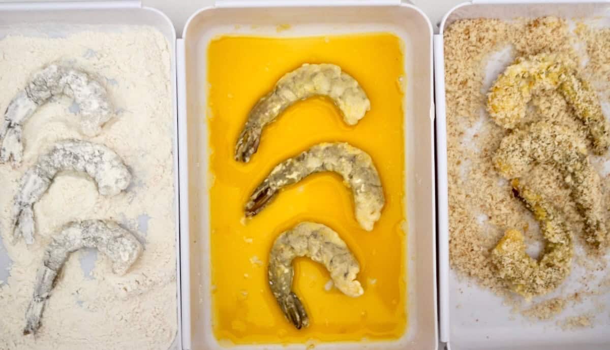 Dredging shrimp in flour, egg and breadcrumbs.