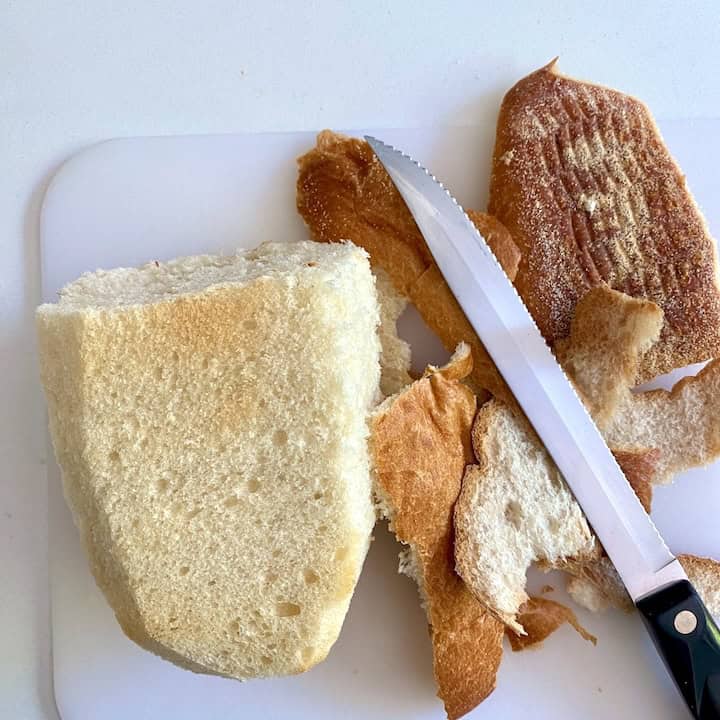 A knife and bread on a cutting board.