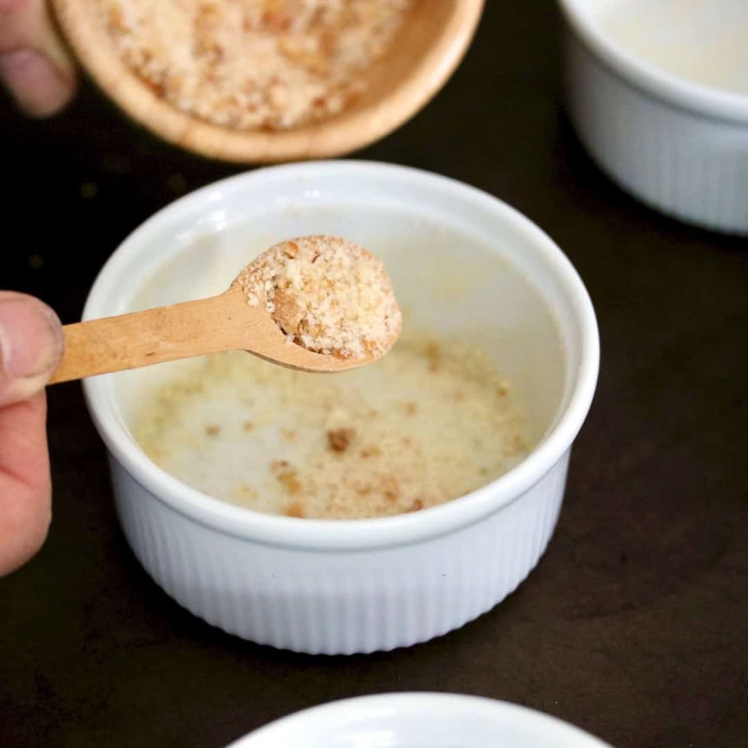 Sprinkling breadcrumbs in a ramekin.