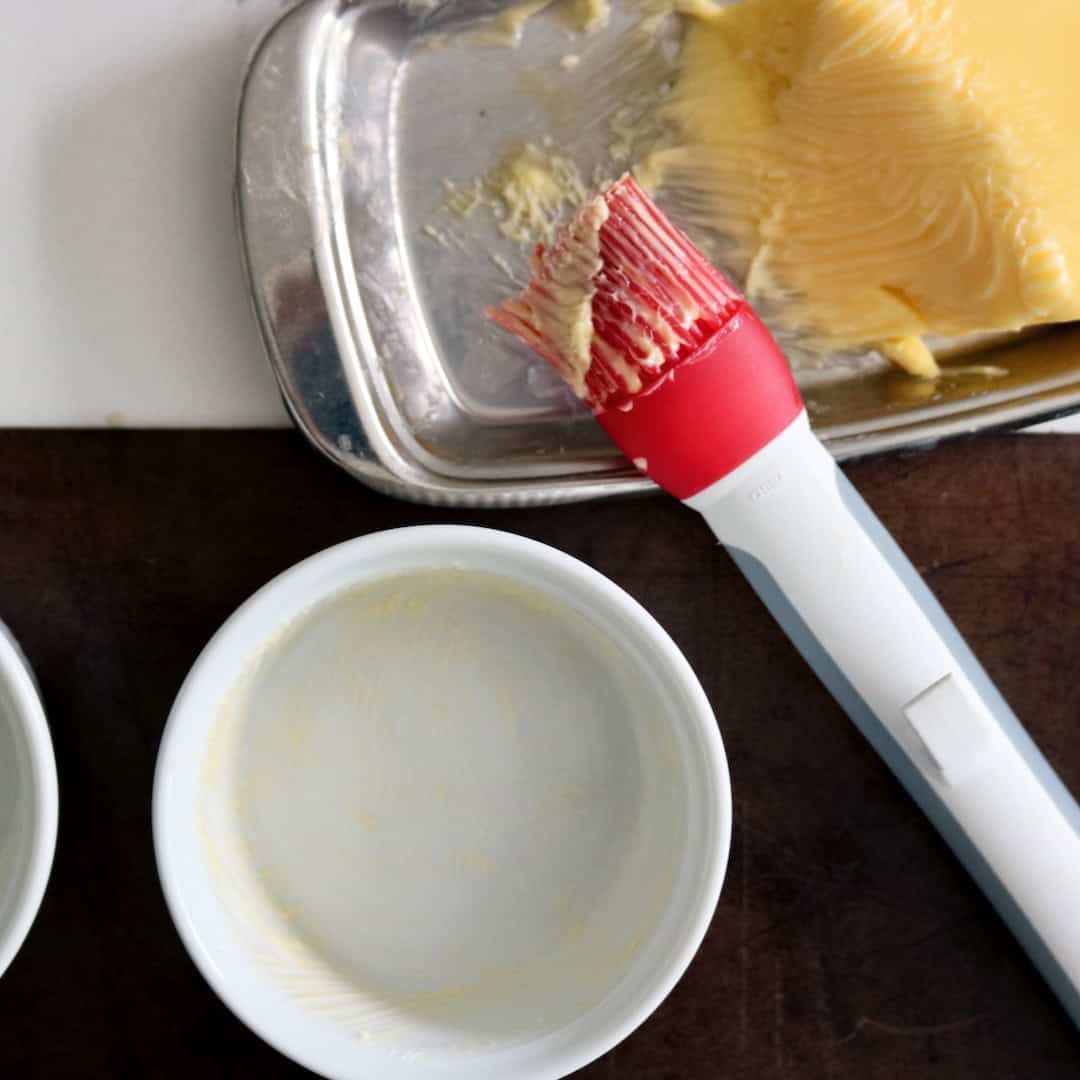 Buttering ramekins.