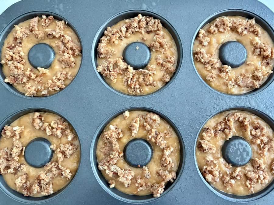 Apple donut batter in a pan topped with crumble.