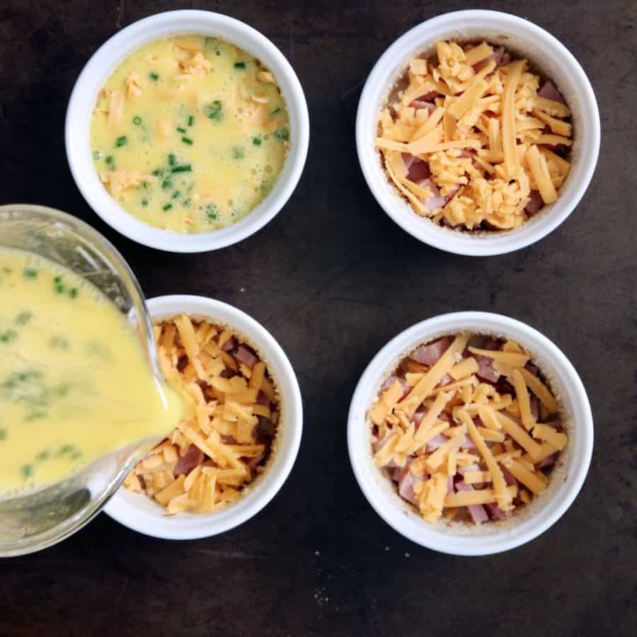 Four bowls filled with ham, cheese and egg mixture.