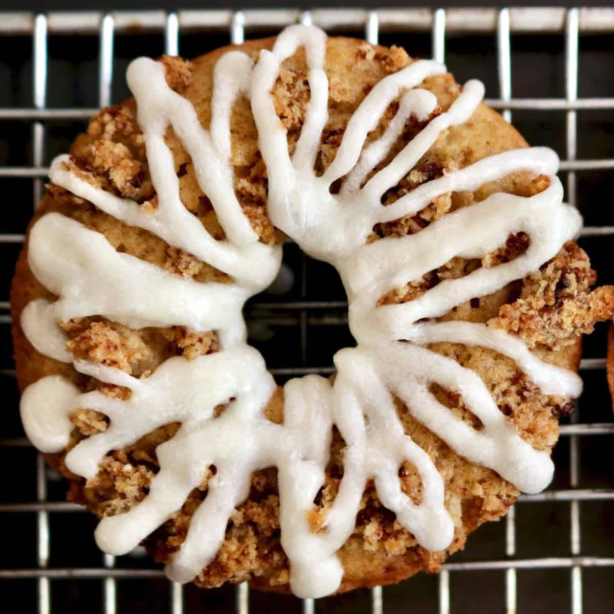 Apple donuts with icing on top of a cooling rack.