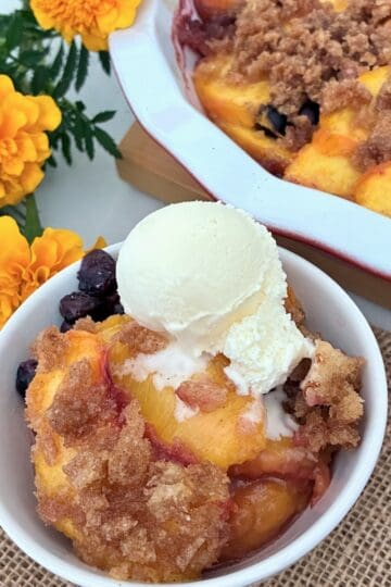 A serving of peach brown Betty with ice cream.