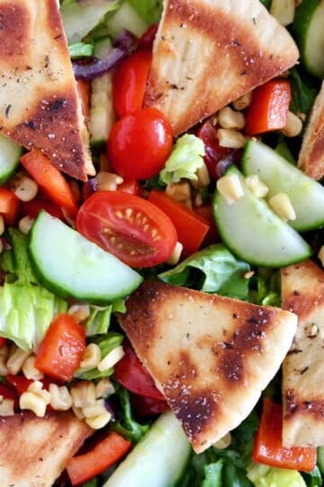 An Israeli salad with pita bread slices and vegetables.