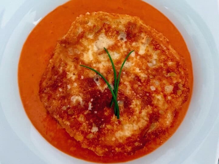 Tomato and grilled cheese soup garnished with chives.