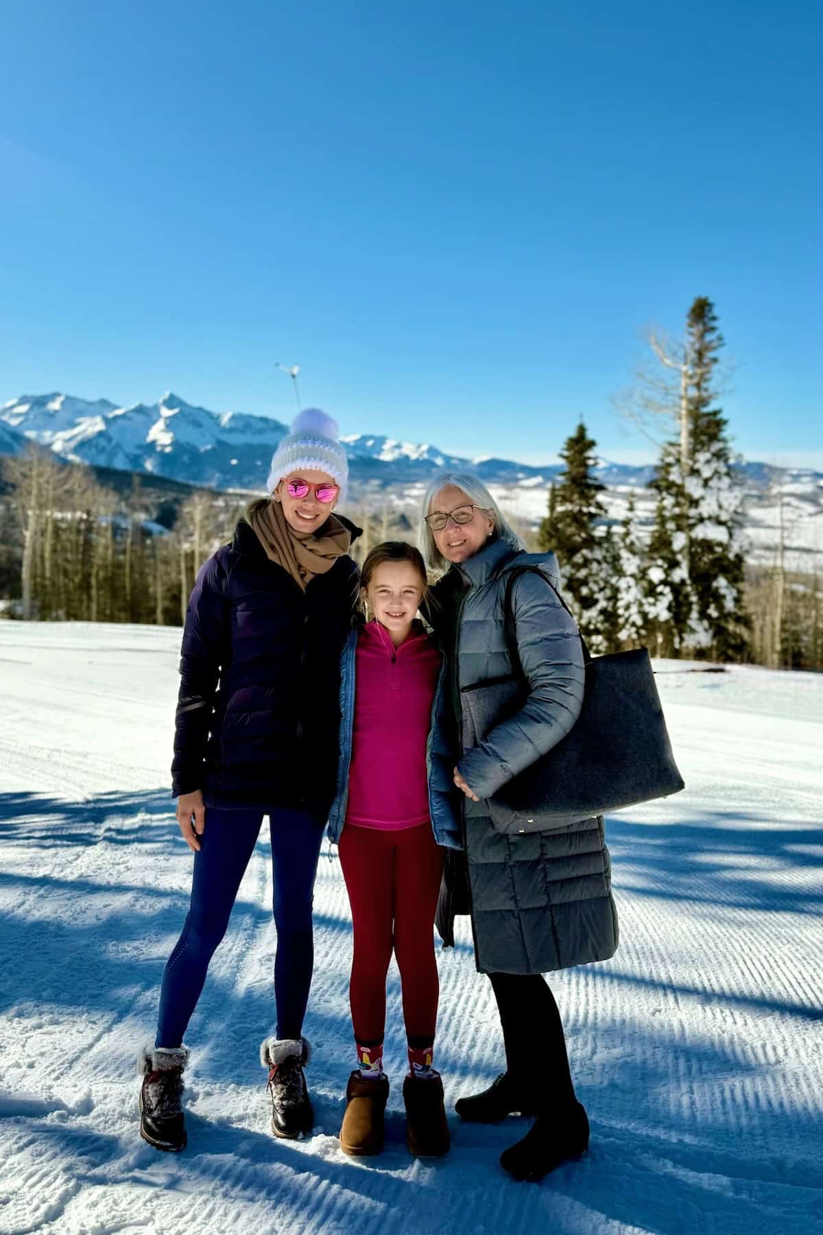 Smiling women and girl enjoying snowy mountain landscape.