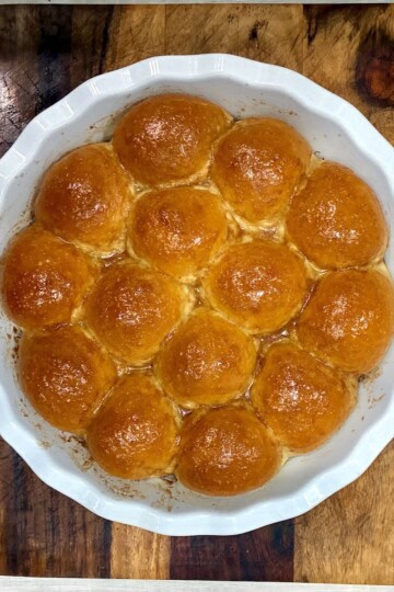 Freshly baked dinner rolls on a white dish.