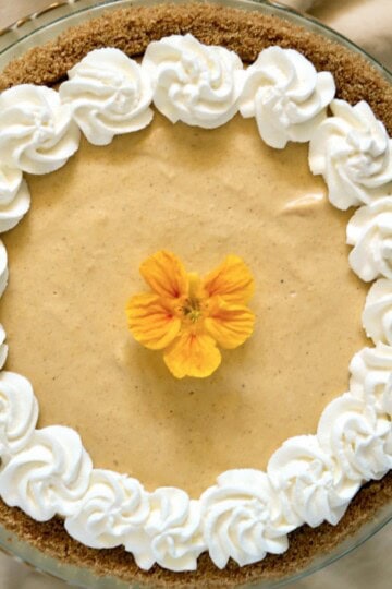 Graham crust pumpkin pie with whipped cream and nasturtium.