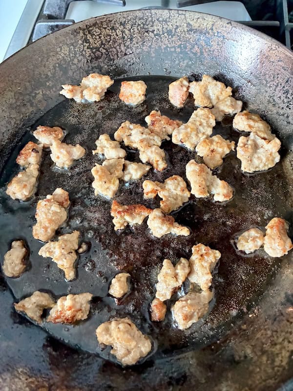 Browning Italian sausage in a pan.