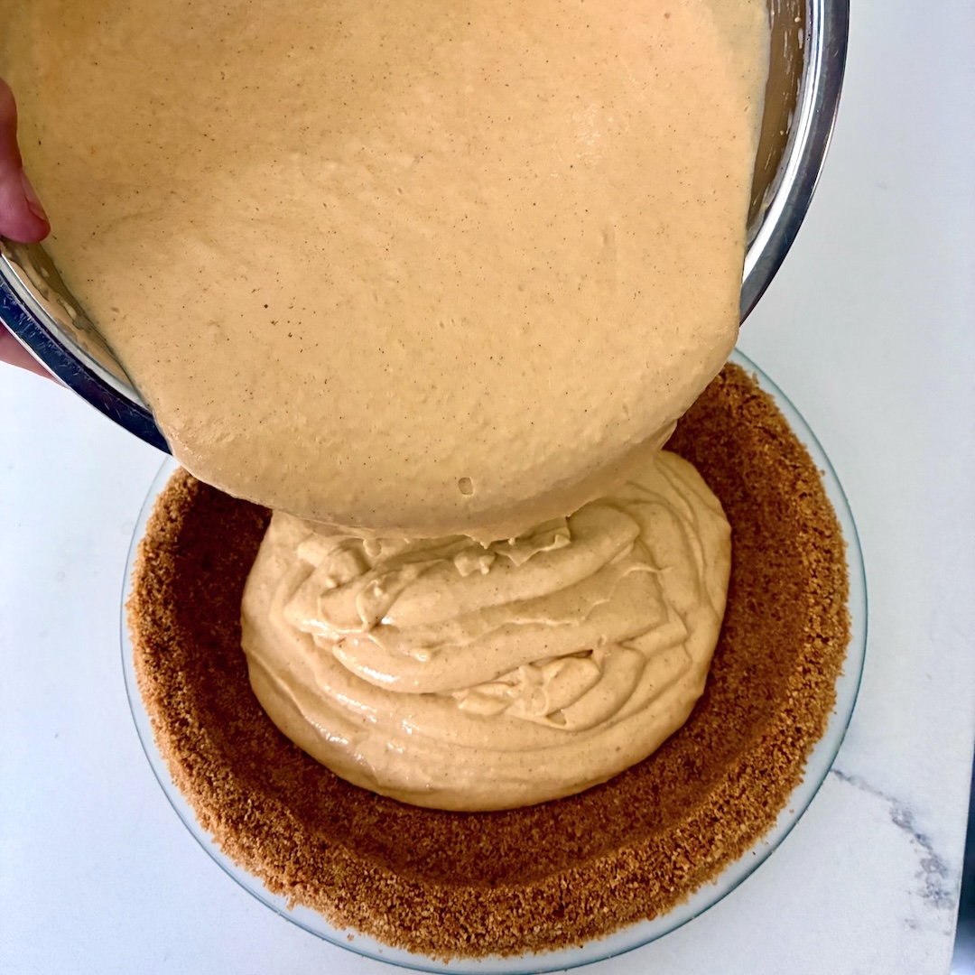 Pouring custard pie filling into crust.
